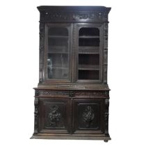 A large Victorian carved oak Bookcase, the upper section enclosed by a pair of arched glazed