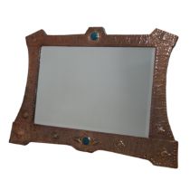 A large Arts and Crafts Copper Wall Mirror, with shaped hammered frame decorated in embossed stars