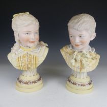 A pair of early 20thC bisque Busts, modelled as a boy and girl, on fluted plinth base, H 29cm (2)