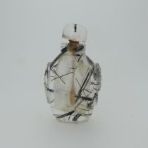 A Chinese rutilated quartz Snuff Bottle and Stopper, of elongated form with relief work heads to