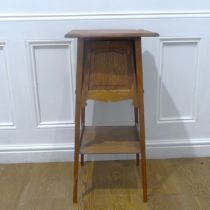 An Arts and Crafts oak Plant Stand/Torchere, moulded top above small cupboard, raised on splayed