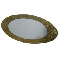 A Glasgow School Arts and Crafts celtic revival brass Mirror, the oval frame repoussé-decorated with