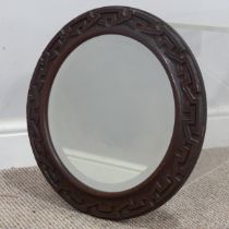 An Arts and Crafts circular wall Mirror, carved oak geometric frame encasing bevelled plate, W 40 cm