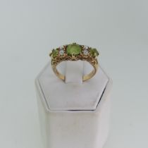 A peridot and seed pearl Ring, the three graduated circular facetted peridot with two vertically set