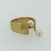 A 9ct yellow gold Ring, the flared front set with two cultured pearls and diamond cut shoulders,