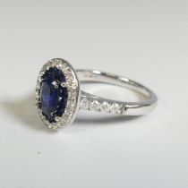 A sapphire and diamond Cluster Ring, the central oval facetted sapphire, approx. 7mm long four