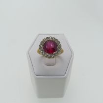A ruby glass Dress Ring, the circular facetted glass within a surround of rose cut diamonds, all