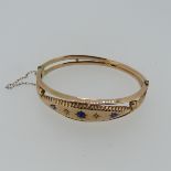 A 9ct rose gold hollow hinged Bangle, the flared front gypsy set with three sapphires and two