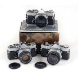 Three Olympus OM-1 SLR Cameras.