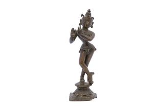 A SOUTH INDIAN POLYCHROME-PAINTED BRONZE FIGURINE OF LORD KRISHNA PLAYING THE FLUTE Possibly Tamil N