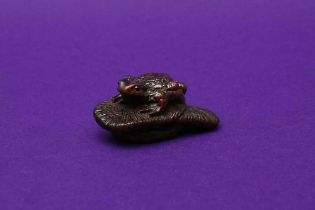 A JAPANESE WOOD NETSUKE OF A TOAD ON A SLIPPER