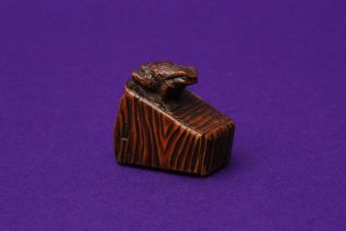 A JAPANESE WOOD NETSUKE OF A TOAD ON A BUCKET