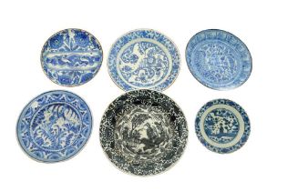 SIX ASIAN-INSPIRED BLUE AND WHITE POTTERY DISHES WITH FIGURAL AND VEGETAL MOTIFS Iran, 18th - 19th c