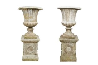 A PAIR OF RECONSTITUTED STONE CAMPANA URNS ON PLINTHS