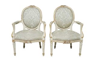 A PAIR OF FRENCH LOUIS XVI STYLE WHITE PAINTED AND PARCEL GILT FAUTEUIL ARMCHAIRS