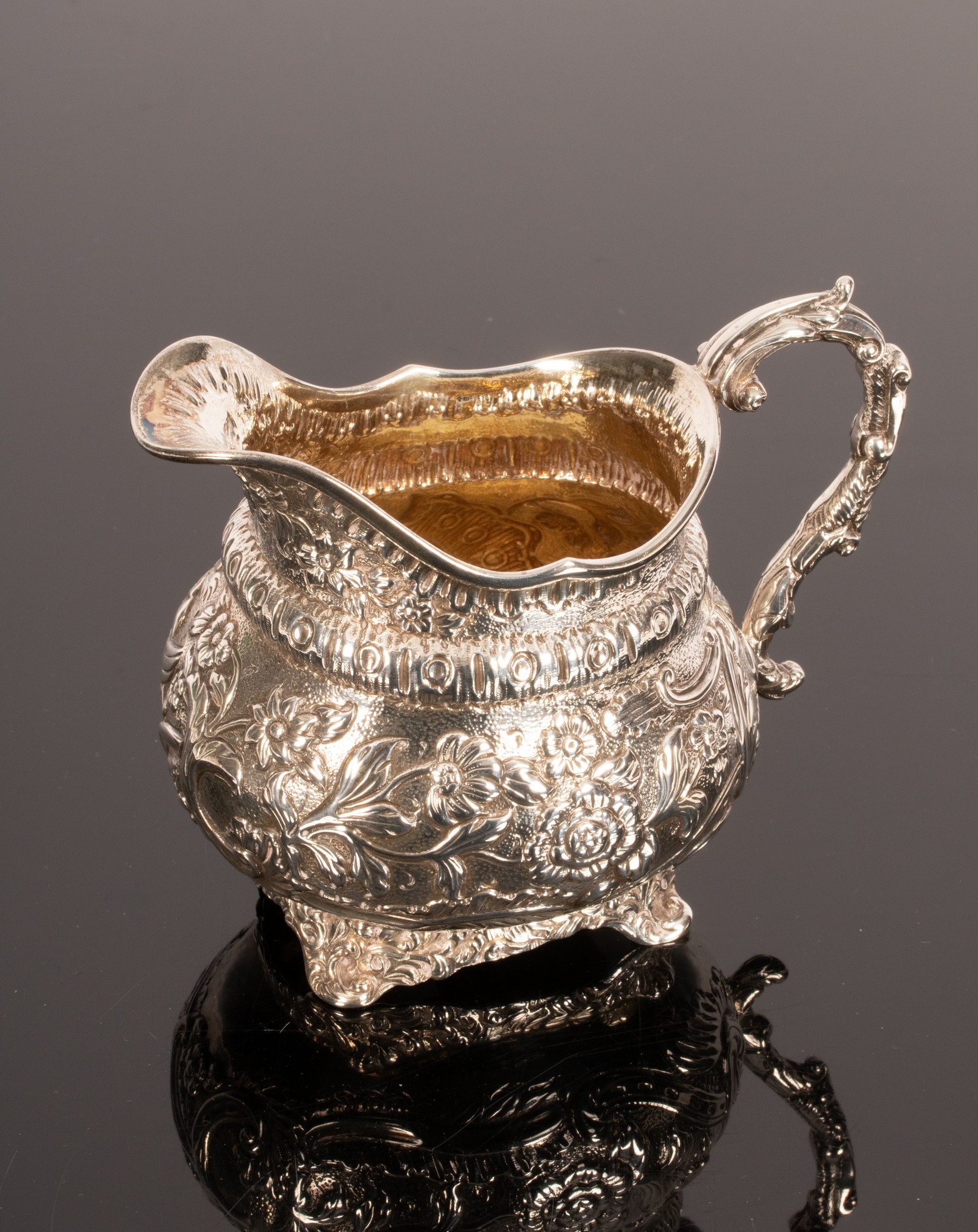 A George III silver and silver gilt jug, London 1817, with embossed decoration throughout,