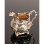 A George III silver and silver gilt jug, London 1817, with embossed decoration throughout,