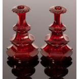 A pair of red Bohemian cut glass bottles, 19th Century, with three tiers of faceted lappets,