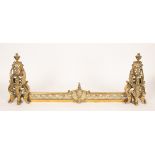 A brass fender with winged griffin supports and urn finials,