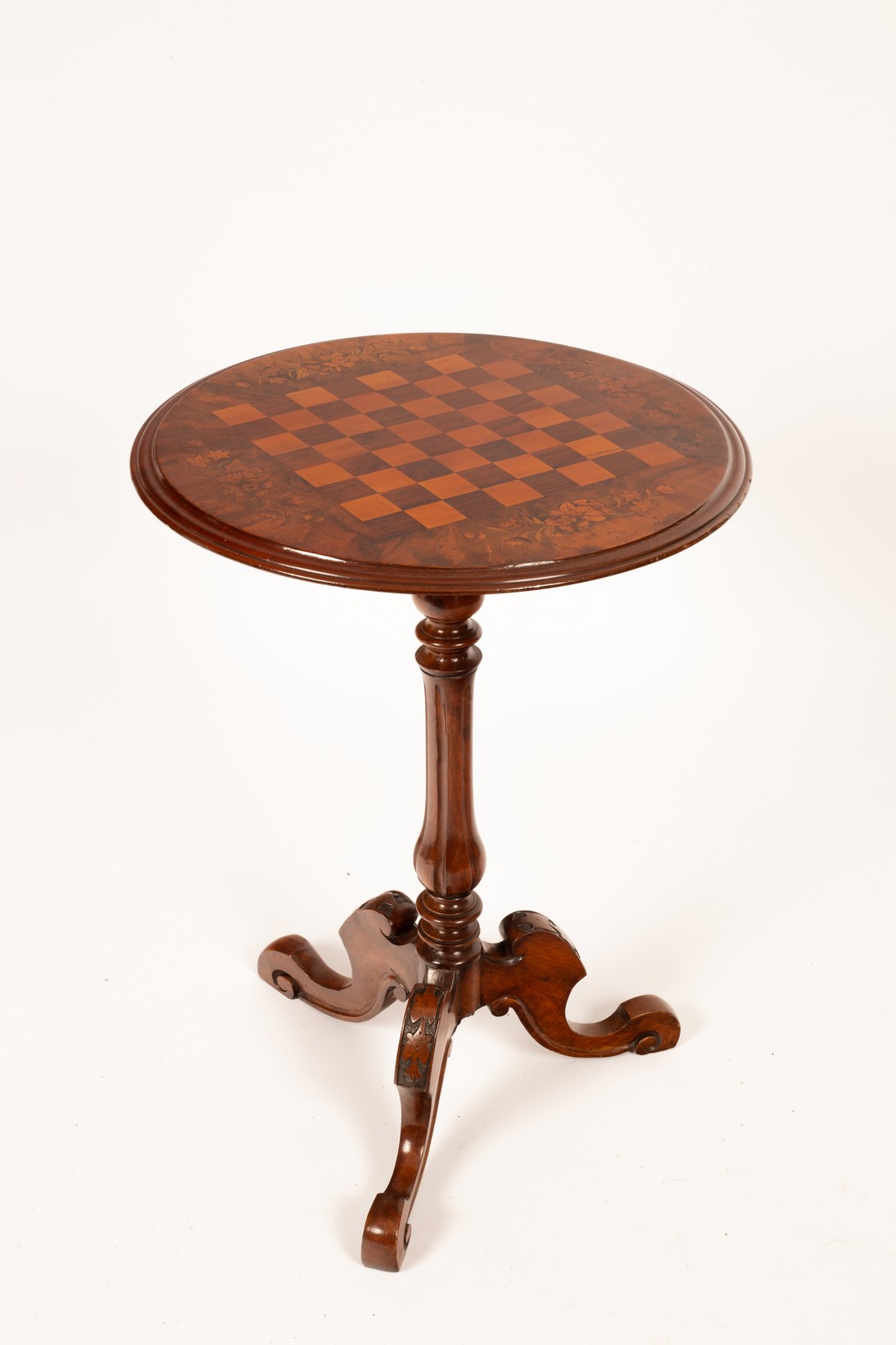 A Victorian walnut table the top inlaid for chess, on a carved tripod support,