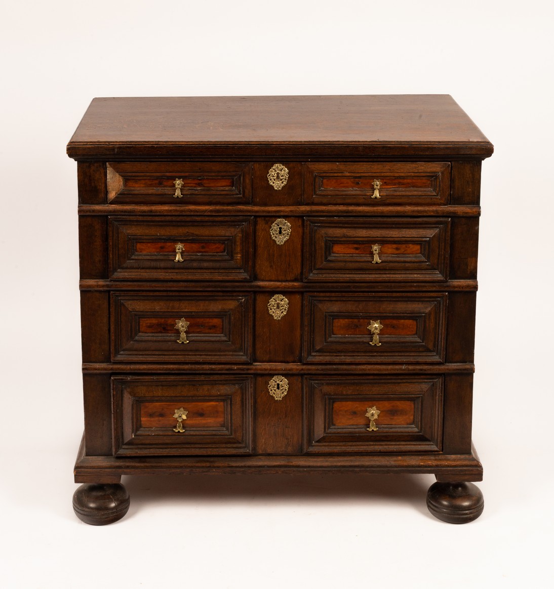 A Jacobean style oak chest of four long drawers on bun feet,