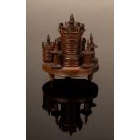 A turned wood etui with central castle pin cushion and surround of two smaller turrets,