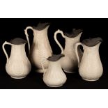 Five saltware jugs, floral decoration, pewter lids, the largest 27.