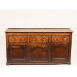 An oak dresser base, three short drawers over two cupboards,