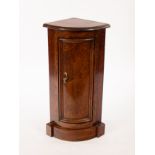 A narrow floor standing bowfronted corner cupboard of small proportions,
