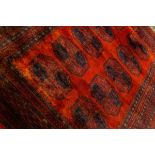 A red Bokhara rug with blue details and geometric medallions,