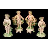 A Derby pair of cherubs with flower baskets, raised on scroll bases and two others, 12.