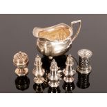 A silver cream jug, Birmingham 1923, of oblong form on ball feet, three baluster silver pepper pots,