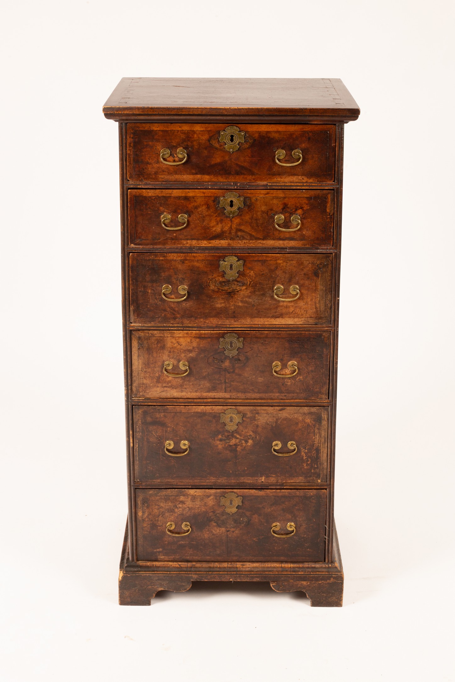 A Queen Anne style walnut tall chest of six drawers, each feather banded and on bracket feet,