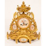 A gilt metal mounted mantel clock, with urn finial and porcelain panels to the sides and base,