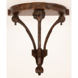 A Neoclassical carved wooden wall bracket with ram's head support,