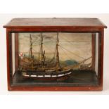 A wooden model of a three-master ship in a glazed case,