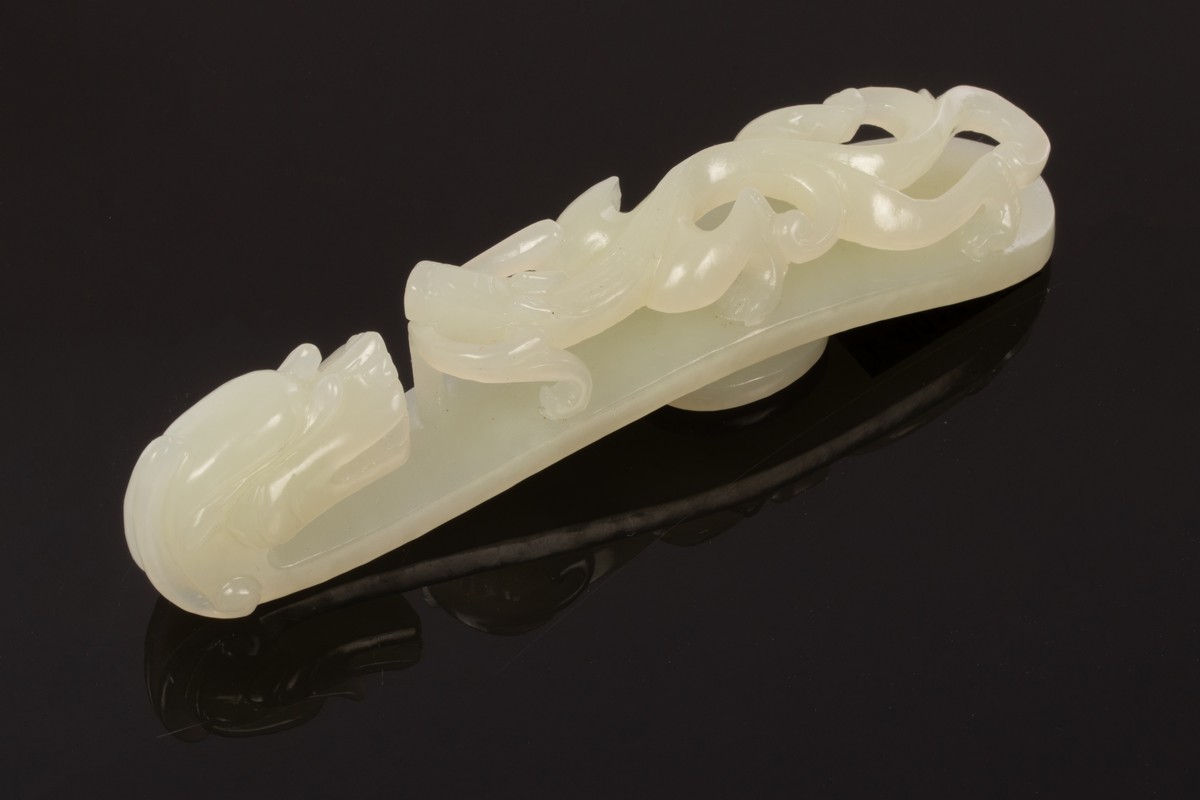 A Chinese white jade carved belt hook, Qing, in the form of a dragon,