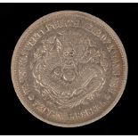 A Chinese silver coin, one side with relief of a dragon, the other marked 'Yi Yuan' (one dollar),