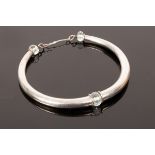 A white metal torc necklace, faceted pale blue bead to centre and terminals,