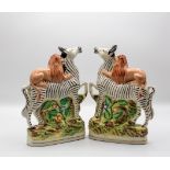 A pair of late 19th Century Staffordshire pottery models of lions attacking zebras,