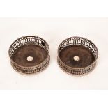 A pair of silver plated mounted wine coasters, circular with pierced sides,