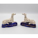 A pair of Staffordshire figures of recumbent Dalmatians on gilt-lined blue oval bases,