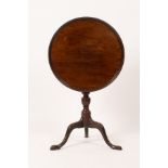 A George III mahogany table, the circular dish top on a turned column and tripod support,