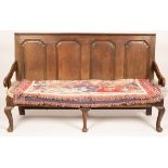 An oak settle, with panelled back on cabriole legs,