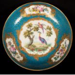 A Sèvres saucer dish with a central reserve of fancy birds and three flowers around,