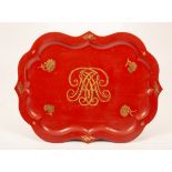 A red and gold lacquer tray with a central monogram,