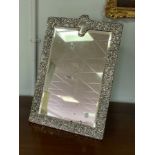 A silver easel back mirror, CD, London 1913, fitted with a bevelled plate within a scrolling frame,