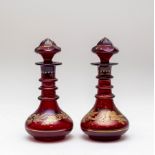 A pair of ruby glass liqueur bottles and stoppers, circa 1900, with triple-ring necks,