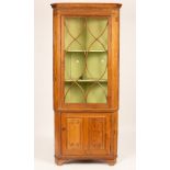 A pine corner cupboard with glazed upper section,