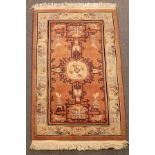 A Chinese superwash rug, the peach field with vases and centred by an ivory medallion of dragons,